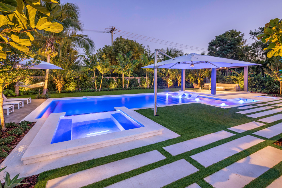 Design ideas for a large modern backyard custom-shaped lap pool in Miami with a hot tub.