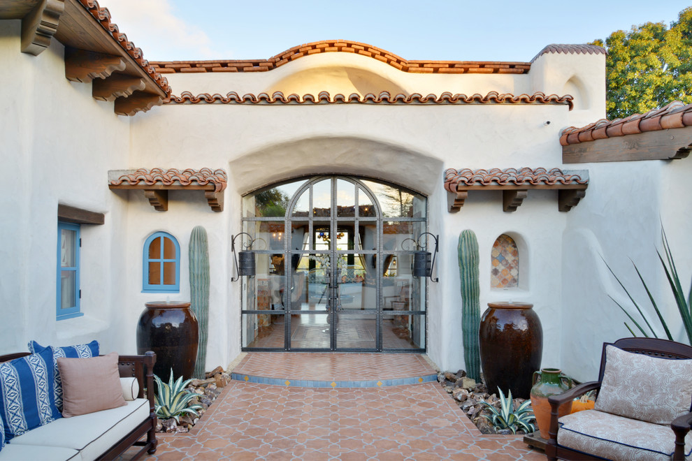 Aménagement d'une très grande porte d'entrée sud-ouest américain avec un mur blanc, un sol en carrelage de céramique, une porte double, une porte en verre et un sol orange.
