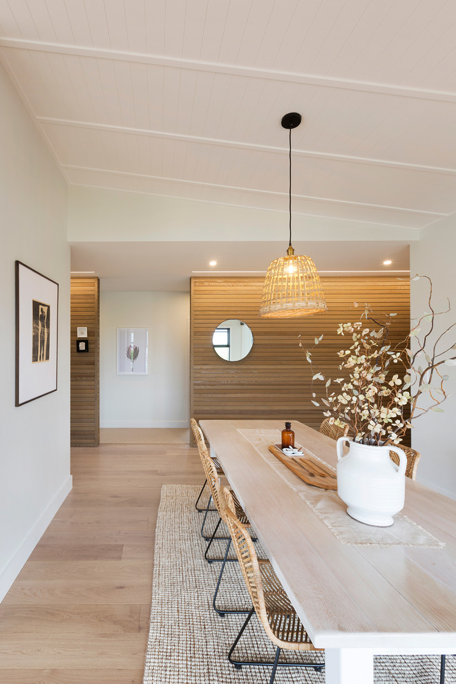 This is an example of a mid-sized scandinavian kitchen/dining combo in Auckland with white walls and light hardwood floors.