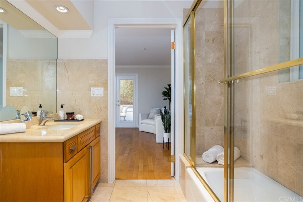 Пример оригинального дизайна: ванная комната среднего размера в стиле модернизм с фасадами в стиле шейкер, коричневыми фасадами, угловой ванной, унитазом-моноблоком, бежевой плиткой, накладной раковиной, бежевым полом, душем с раздвижными дверями, бежевой столешницей, тумбой под одну раковину, встроенной тумбой, душевой кабиной, сиденьем для душа, многоуровневым потолком, душем в нише, мраморной плиткой, бежевыми стенами, мраморным полом и столешницей из кварцита