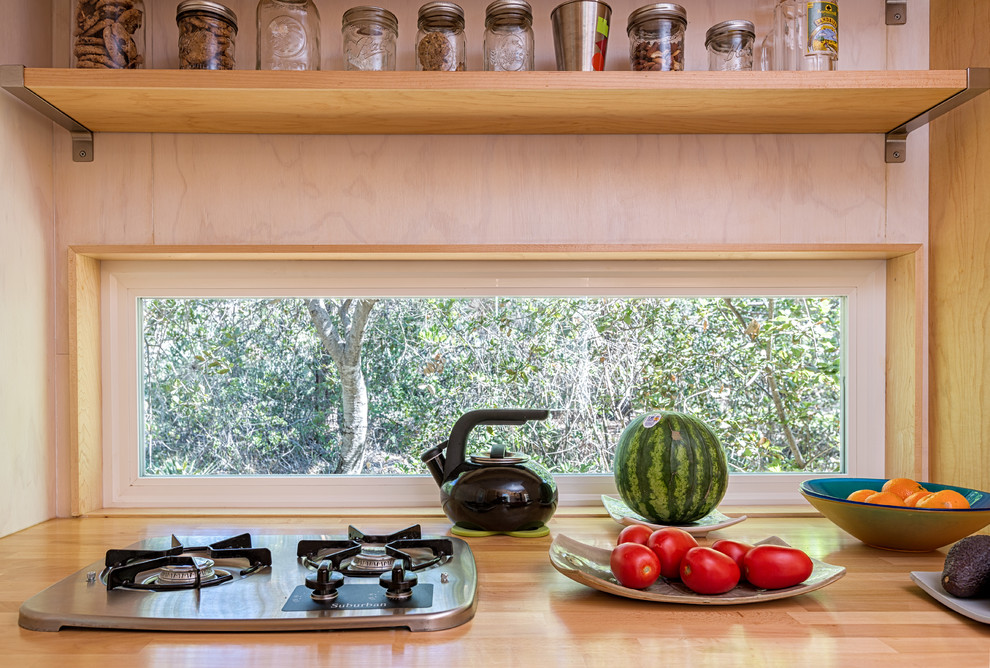 Small trendy galley medium tone wood floor eat-in kitchen photo in Los Angeles with a single-bowl sink, flat-panel cabinets, light wood cabinets, wood countertops, stainless steel appliances and no island