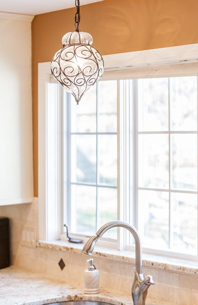 Inspiration for a mid-sized transitional u-shaped light wood floor enclosed kitchen remodel in Boston with a double-bowl sink, recessed-panel cabinets, white cabinets, granite countertops, beige backsplash, stone tile backsplash, stainless steel appliances and an island