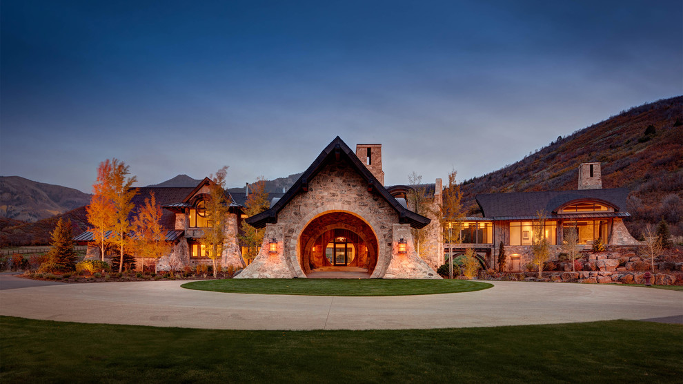 This is an example of an expansive country two-storey grey house exterior in Salt Lake City with stone veneer, a gable roof and a shingle roof.