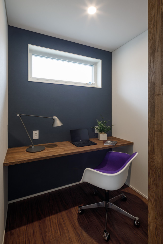 На фото: рабочее место в скандинавском стиле с встроенным рабочим столом, коричневым полом, потолком с обоями, обоями на стенах и синими стенами с