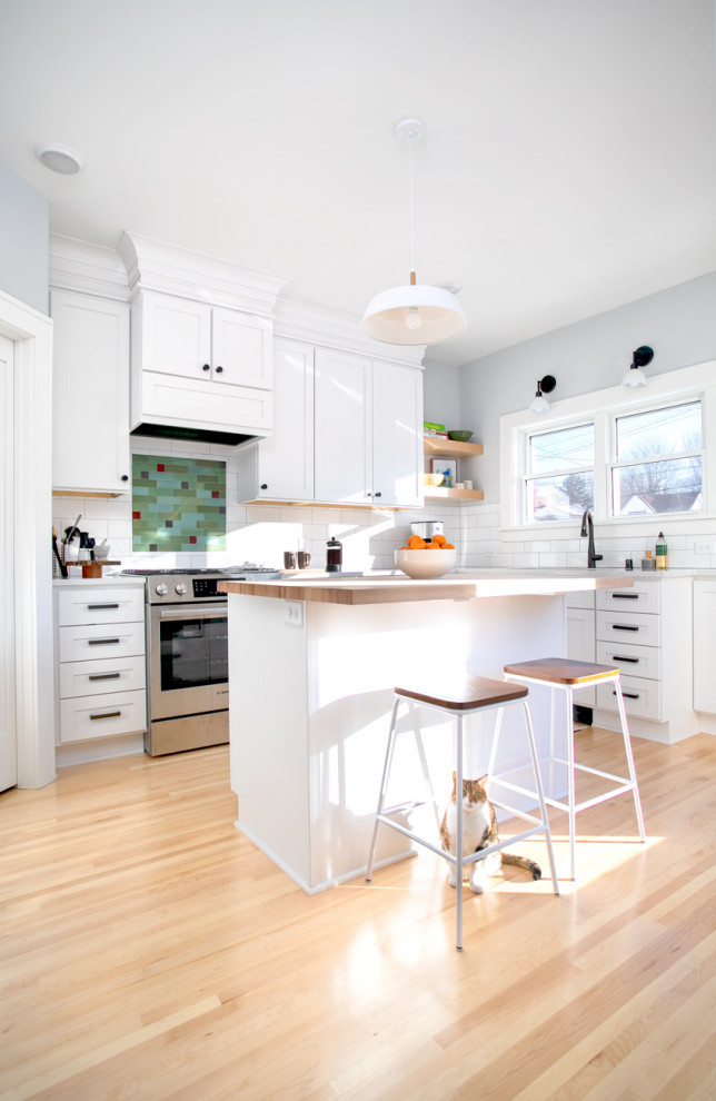 Photo of a mid-sized transitional l-shaped kitchen in Minneapolis with an undermount sink, shaker cabinets, white cabinets, quartz benchtops, white splashback, subway tile splashback, stainless steel appliances, light hardwood floors, with island, white benchtop and beige floor.