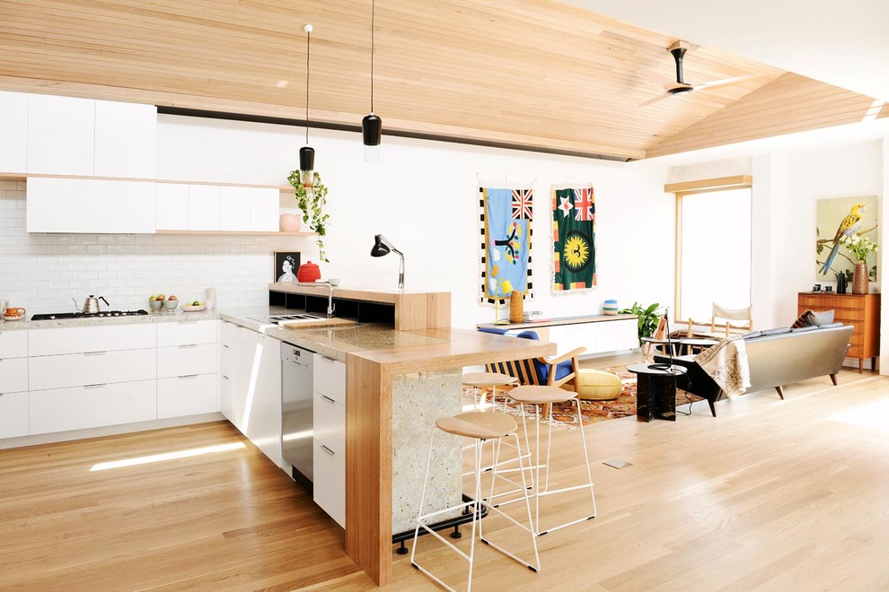Mid-sized scandinavian u-shaped eat-in kitchen in Melbourne with a double-bowl sink, flat-panel cabinets, white cabinets, white splashback, ceramic splashback, stainless steel appliances and light hardwood floors.