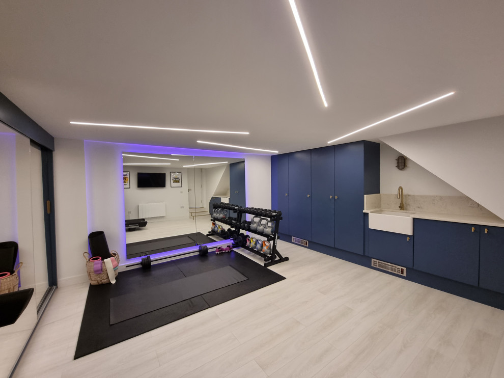 This is an example of a mid-sized contemporary multipurpose gym in London with white walls, laminate floors, multi-coloured floor and recessed.