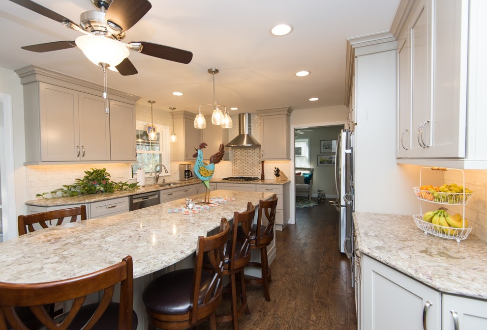 Example of a transitional u-shaped vinyl floor and brown floor eat-in kitchen design with an undermount sink, shaker cabinets, quartz countertops, subway tile backsplash, stainless steel appliances and an island