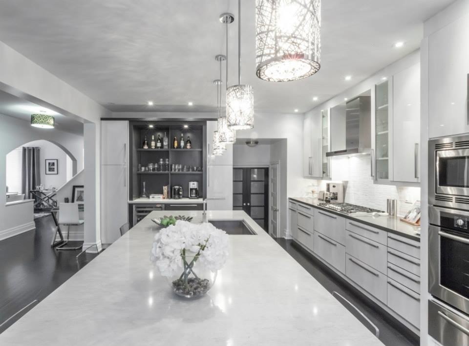 Design ideas for a large modern u-shaped eat-in kitchen in Toronto with an undermount sink, glass-front cabinets, white cabinets, quartzite benchtops, white splashback, stone tile splashback, stainless steel appliances, dark hardwood floors and multiple islands.