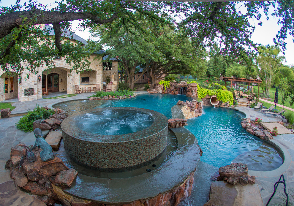 This is an example of a large traditional backyard custom-shaped natural pool in Dallas with a hot tub and natural stone pavers.