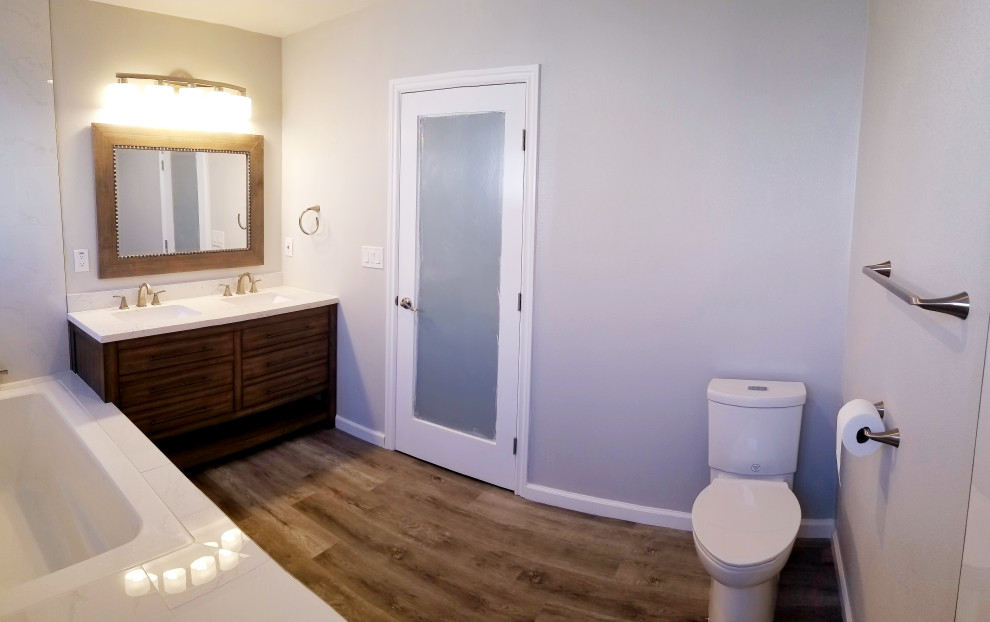На фото: главная ванная комната среднего размера в современном стиле с плоскими фасадами, коричневыми фасадами, японской ванной, угловым душем, раздельным унитазом, белой плиткой, керамогранитной плиткой, серыми стенами, полом из винила, врезной раковиной, столешницей из кварцита, серым полом, душем с распашными дверями, белой столешницей, тумбой под две раковины и напольной тумбой