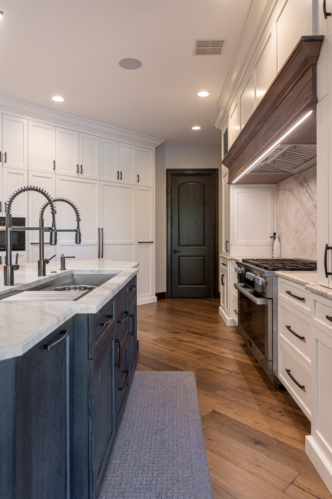 Example of a large transitional medium tone wood floor and brown floor open concept kitchen design with a double-bowl sink, flat-panel cabinets, white cabinets, quartzite countertops, beige backsplash, stainless steel appliances, an island and beige countertops