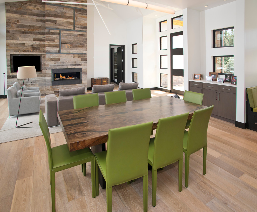 Inspiration for a large modern kitchen/dining combo in Denver with white walls, light hardwood floors, a ribbon fireplace and a wood fireplace surround.