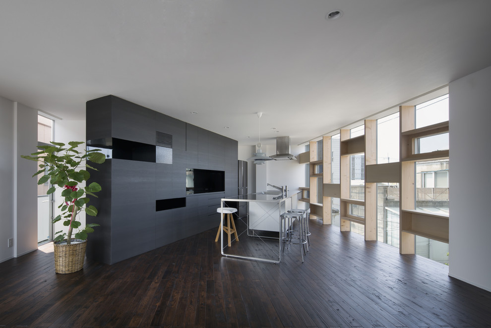 Modern single-wall open plan kitchen with stainless steel benchtops, metallic splashback, with island, an integrated sink, dark hardwood floors and brown floor.