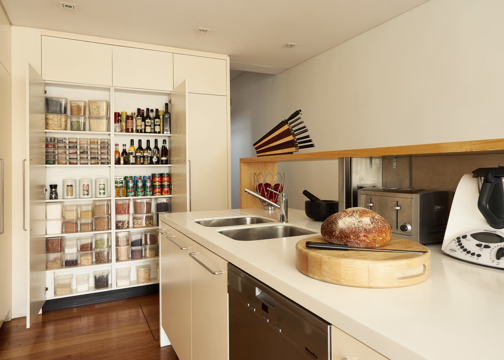 This is an example of a contemporary kitchen in Sydney with an undermount sink, flat-panel cabinets, white cabinets, stainless steel appliances and dark hardwood floors.