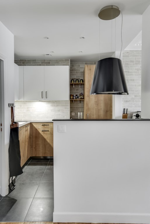 Inspiration for a mid-sized scandinavian u-shaped open plan kitchen in Paris with an integrated sink, flat-panel cabinets, white cabinets, laminate benchtops, grey splashback, ceramic splashback, panelled appliances, ceramic floors, grey floor and black benchtop.