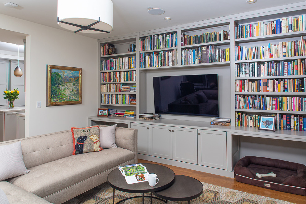 Foto de sala de estar con biblioteca cerrada de tamaño medio con paredes blancas, suelo de madera oscura, televisor colgado en la pared y suelo marrón