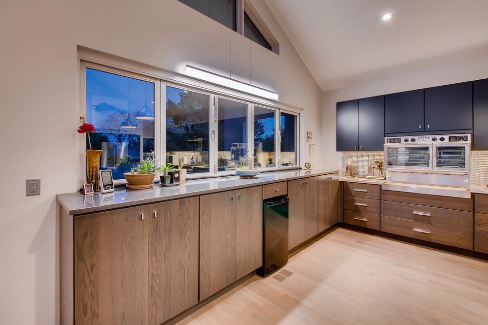 This is an example of an expansive modern u-shaped eat-in kitchen in Denver with an undermount sink, flat-panel cabinets, blue cabinets, quartz benchtops, metallic splashback, metal splashback, stainless steel appliances, medium hardwood floors, with island, brown floor and white benchtop.