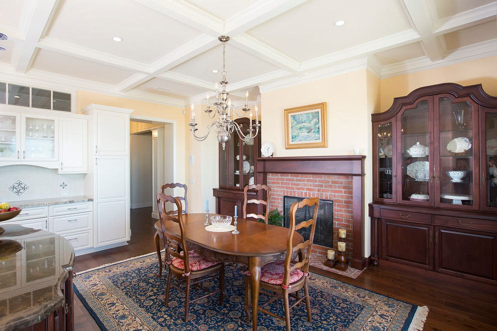 This is an example of a mid-sized traditional kitchen/dining combo in San Diego with yellow walls, dark hardwood floors, a standard fireplace and a brick fireplace surround.