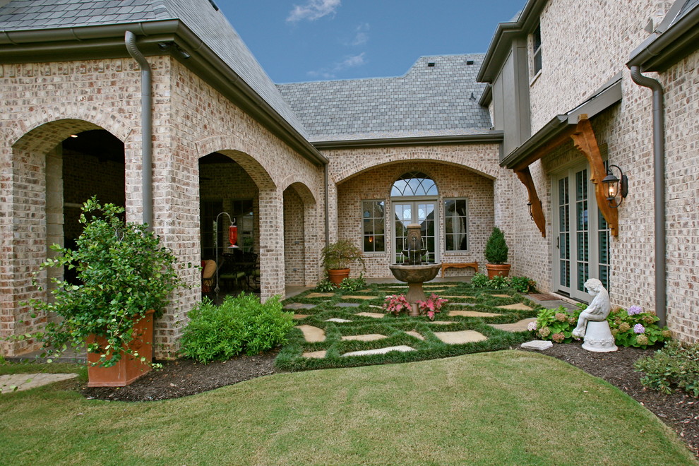 Inspiration for a mid-sized traditional courtyard partial sun garden for summer in Dallas with natural stone pavers and a garden path.