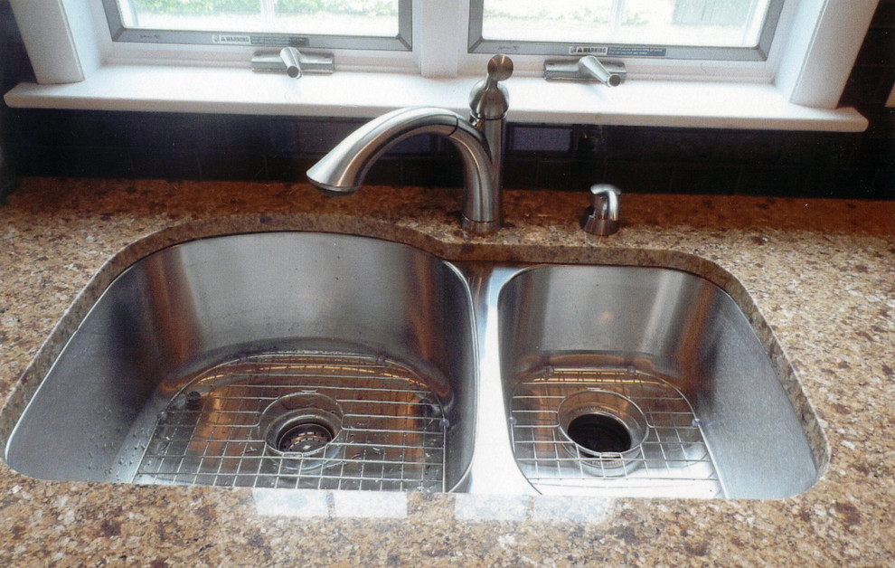 Example of a mid-sized transitional l-shaped laminate floor and yellow floor kitchen pantry design with an undermount sink, recessed-panel cabinets, white cabinets, granite countertops, brown backsplash, ceramic backsplash, stainless steel appliances, no island and beige countertops