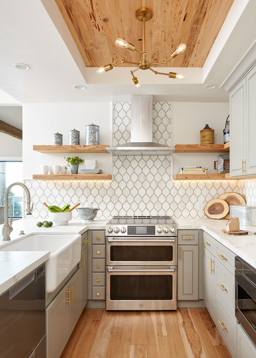 Compact U-shaped kitchen with gray RTA cabinets, patterned backsplash, wood ceiling accents, and open wooden shelves.