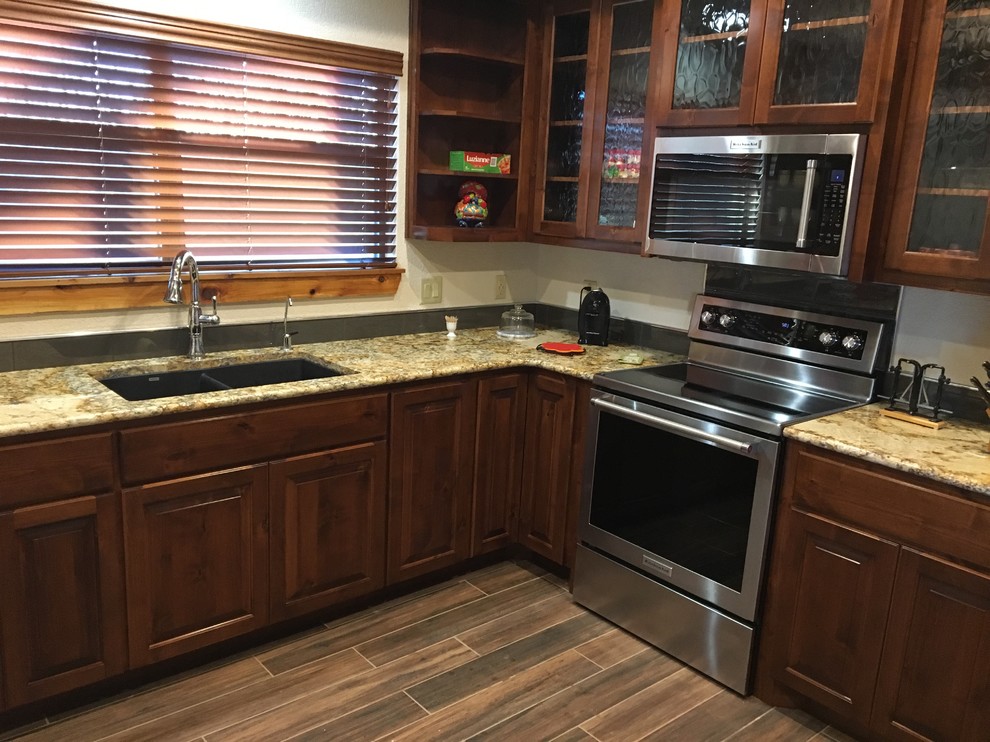 Mid-sized transitional u-shaped porcelain tile and brown floor kitchen photo with an undermount sink, raised-panel cabinets, dark wood cabinets, granite countertops, stainless steel appliances and multicolored countertops