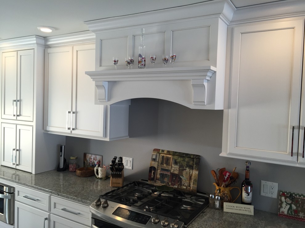 Large transitional l-shaped porcelain tile and gray floor eat-in kitchen photo with an undermount sink, shaker cabinets, white cabinets, granite countertops, stainless steel appliances and no island
