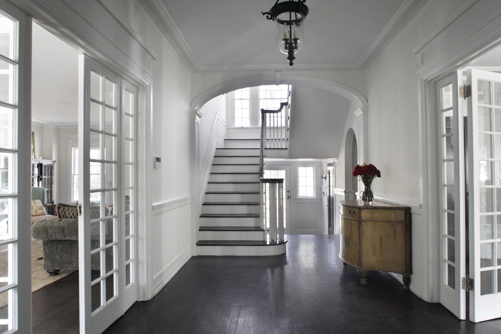 Photo of a traditional foyer in New York with white walls and dark hardwood floors.