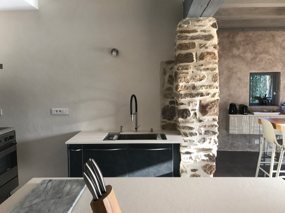 Design ideas for a contemporary u-shaped separate kitchen in Angers with beaded inset cabinets, stainless steel cabinets, solid surface benchtops, black splashback, glass sheet splashback, stainless steel appliances, cement tiles, multiple islands and grey floor.