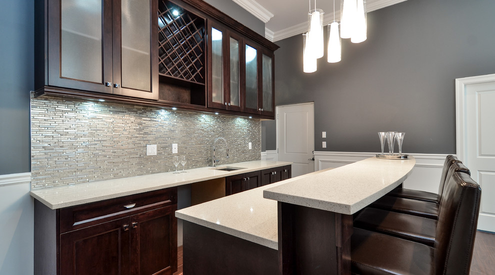 Inspiration for a mid-sized contemporary galley seated home bar in Vancouver with shaker cabinets, dark wood cabinets, an undermount sink, quartzite benchtops, grey splashback, glass tile splashback and medium hardwood floors.