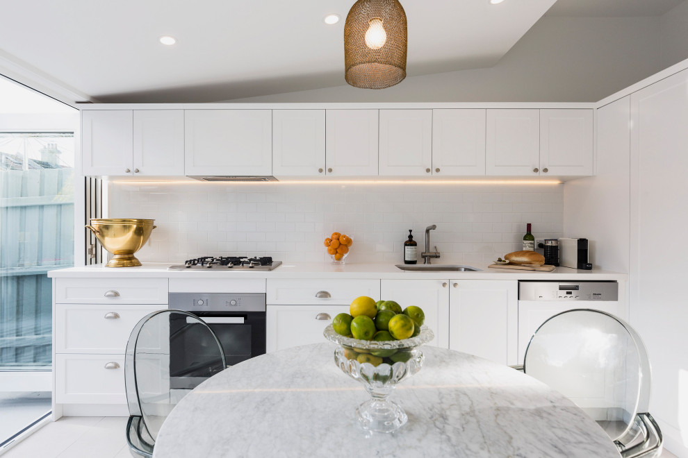 Inspiration for a contemporary single-wall kitchen in Sydney with an undermount sink, shaker cabinets, white cabinets, white splashback, subway tile splashback, stainless steel appliances, grey floor, white benchtop and vaulted.