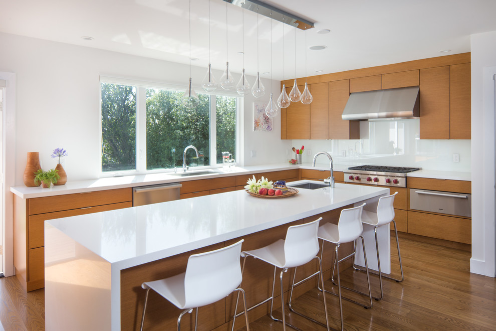 Photo of a large contemporary l-shaped kitchen in San Francisco with an undermount sink, medium wood cabinets, quartz benchtops, white splashback, glass sheet splashback, stainless steel appliances, medium hardwood floors, with island, flat-panel cabinets and brown floor.