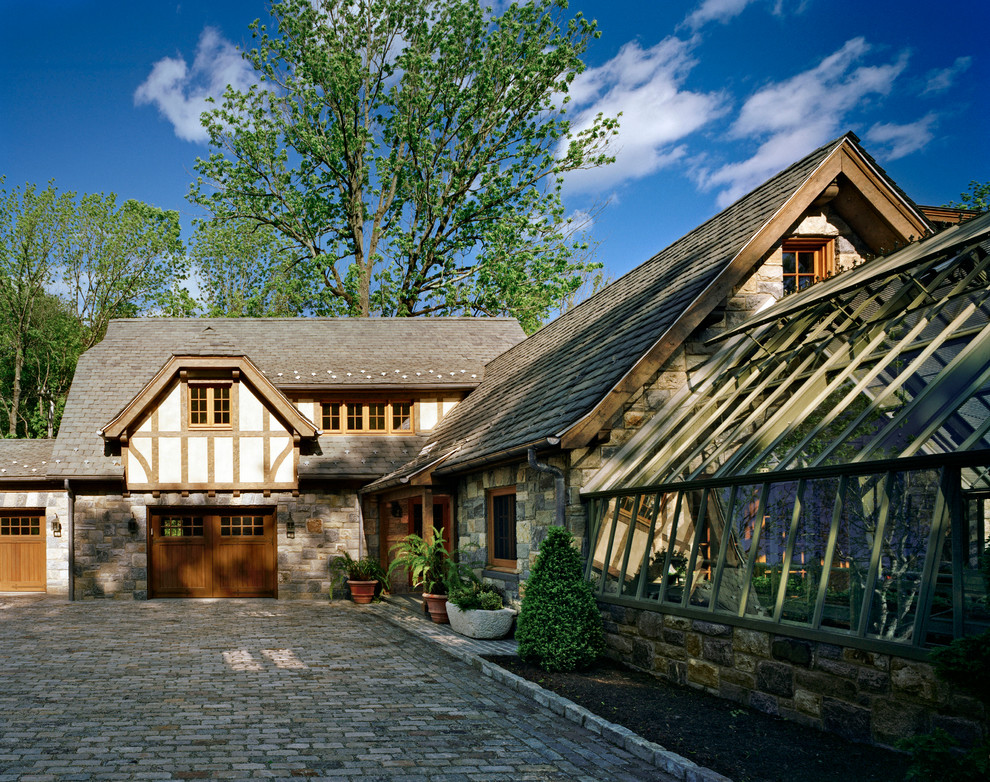 Design ideas for a two-storey exterior in New York with stone veneer and a clipped gable roof.