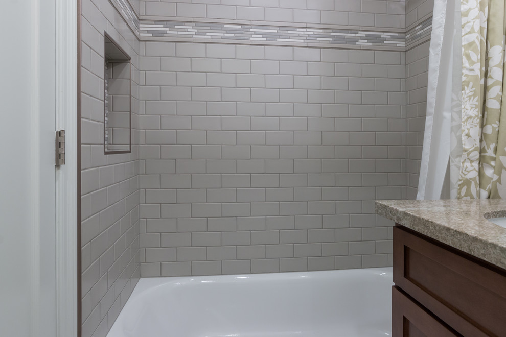 This is an example of a mid-sized transitional bathroom in Los Angeles with shaker cabinets, medium wood cabinets, an alcove tub, a shower/bathtub combo, a two-piece toilet, green tile, ceramic tile, green walls, porcelain floors, an undermount sink, granite benchtops, grey floor and a shower curtain.