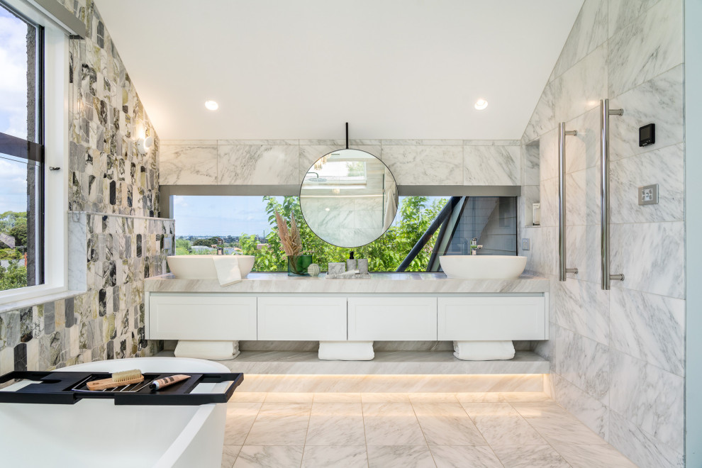 Photo of a mid-sized contemporary master bathroom in Melbourne with recessed-panel cabinets, white cabinets, a freestanding tub, a double shower, white tile, marble, white walls, marble floors, a vessel sink, marble benchtops, multi-coloured floor, a hinged shower door, multi-coloured benchtops, a niche, a double vanity, a floating vanity and vaulted.