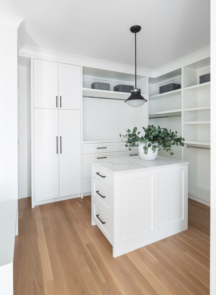 Foto di una cabina armadio minimal con ante in stile shaker, ante bianche e pavimento in legno massello medio