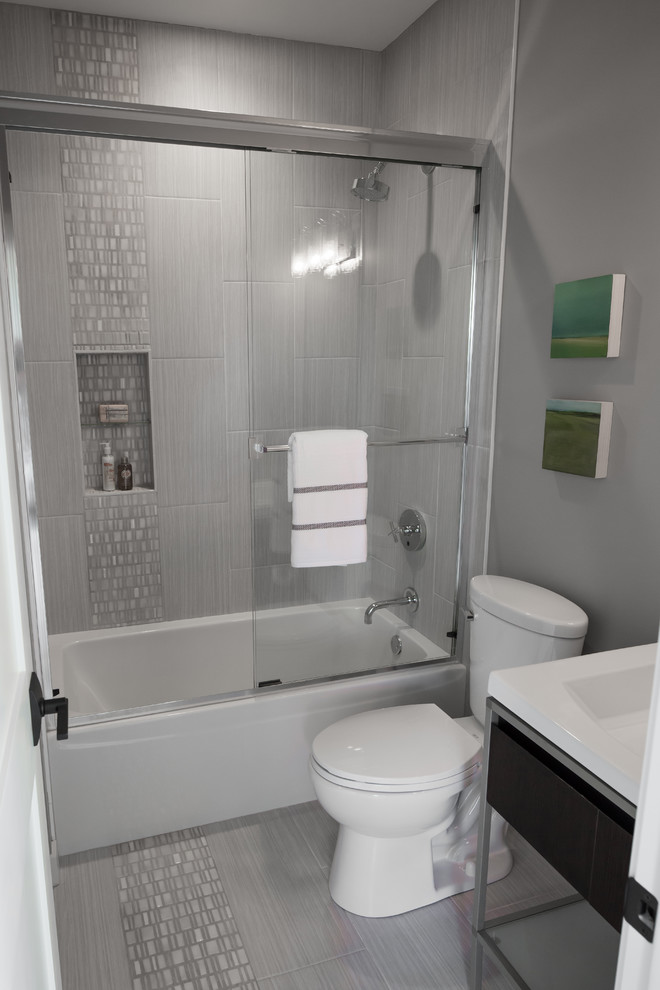 Small contemporary bathroom in Minneapolis with a console sink, flat-panel cabinets, dark wood cabinets, solid surface benchtops, an alcove tub, an alcove shower, a one-piece toilet, gray tile, ceramic tile, grey walls and ceramic floors.