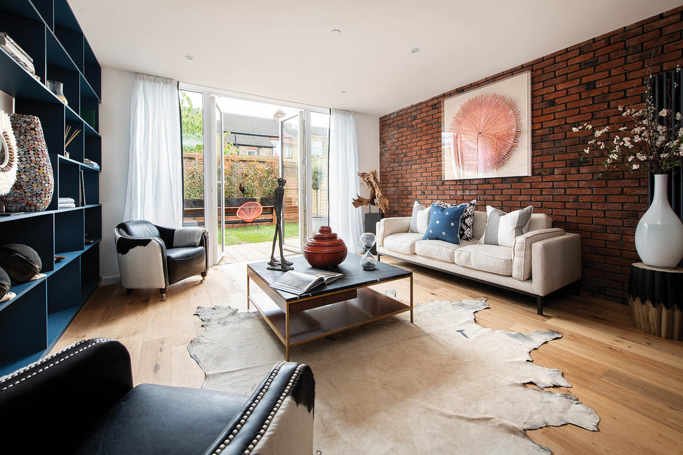 Inspiration for a contemporary living room in London with light hardwood floors, no fireplace and brick walls.