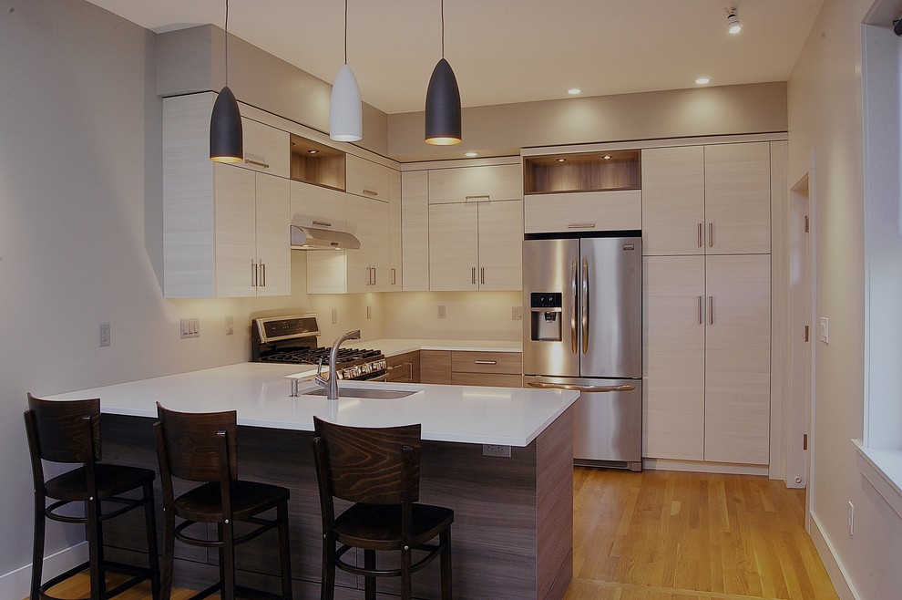 Inspiration for a mid-sized contemporary u-shaped kitchen in Boston with an undermount sink, flat-panel cabinets, light wood cabinets, quartz benchtops, stainless steel appliances, light hardwood floors and a peninsula.