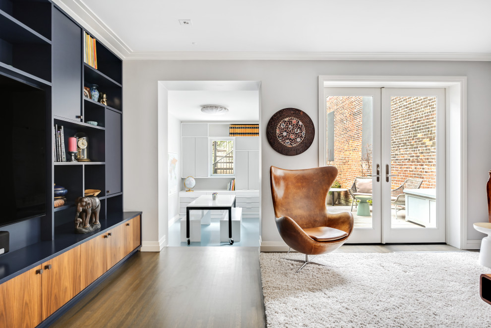 Contemporary enclosed family room in New York with a library, white walls, medium hardwood floors, no fireplace, a built-in media wall and brown floor.