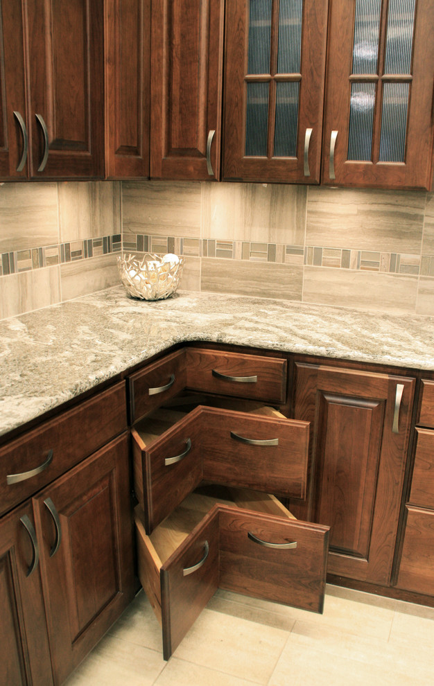 Eat-in kitchen - large transitional l-shaped ceramic tile eat-in kitchen idea with raised-panel cabinets, medium tone wood cabinets, gray backsplash, mosaic tile backsplash, an island, stainless steel appliances and quartz countertops