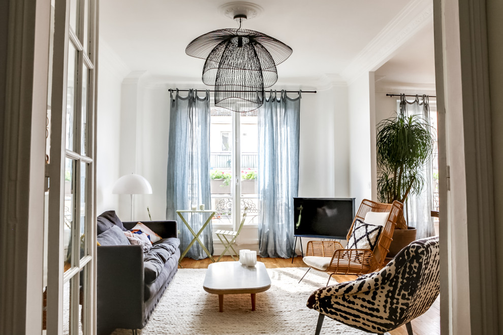 Foto di un grande soggiorno bohémian aperto con pareti bianche, pavimento in legno massello medio e TV autoportante