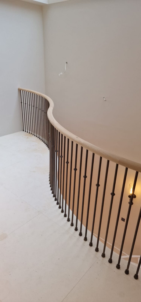 Large modern spiral mixed railing staircase in London with limestone treads and limestone risers.