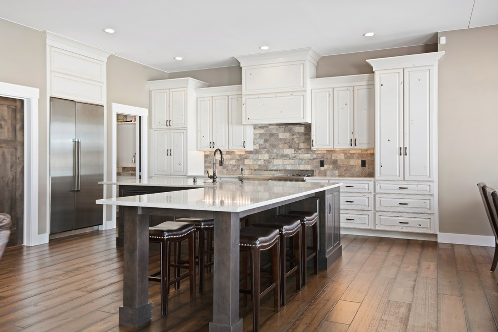 Eat-in kitchen - large transitional l-shaped medium tone wood floor and brown floor eat-in kitchen idea with an undermount sink, raised-panel cabinets, quartz countertops, beige backsplash, stone tile backsplash, stainless steel appliances, an island and beige countertops