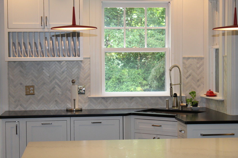 Inspiration for a large transitional dark wood floor and brown floor enclosed kitchen remodel in Boston with a single-bowl sink, shaker cabinets, white cabinets, soapstone countertops, gray backsplash, marble backsplash, stainless steel appliances and an island