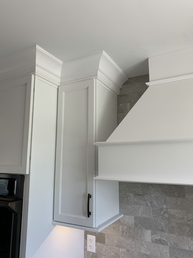 Large transitional l-shaped vinyl floor and gray floor eat-in kitchen photo with an undermount sink, recessed-panel cabinets, white cabinets, quartz countertops, gray backsplash, ceramic backsplash, stainless steel appliances, an island and white countertops