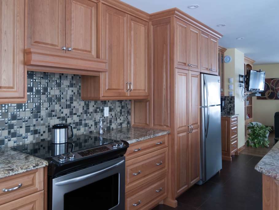 Enclosed kitchen - mid-sized transitional single-wall porcelain tile and brown floor enclosed kitchen idea with a double-bowl sink, raised-panel cabinets, light wood cabinets, granite countertops, gray backsplash, glass tile backsplash, stainless steel appliances and an island