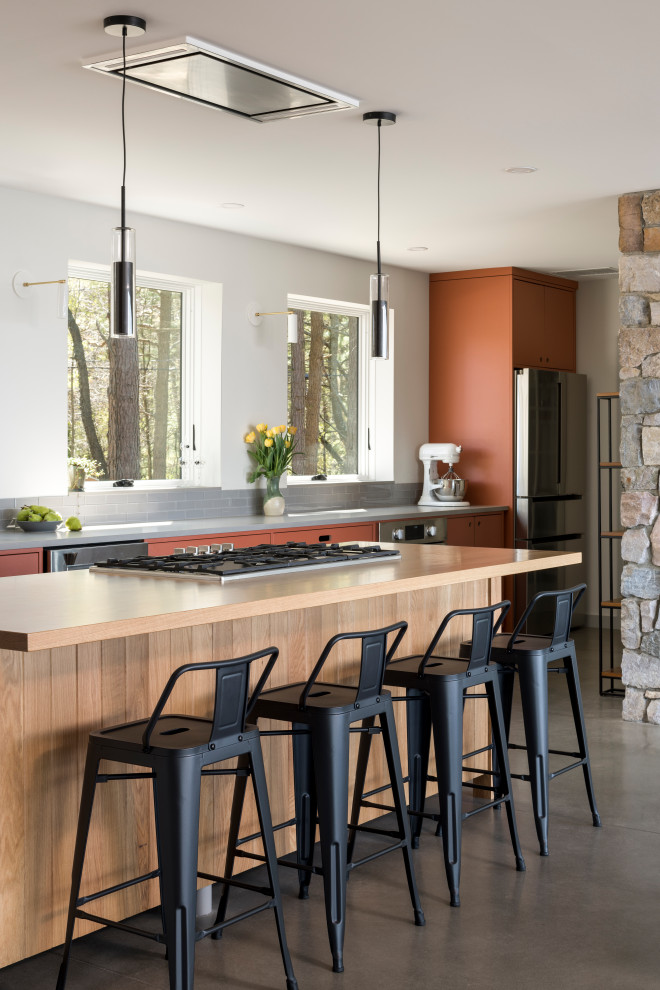 Inspiration for a mid-sized modern open plan kitchen in New York with an undermount sink, flat-panel cabinets, orange cabinets, quartz benchtops, grey splashback, glass tile splashback, stainless steel appliances, concrete floors, with island, grey floor and grey benchtop.