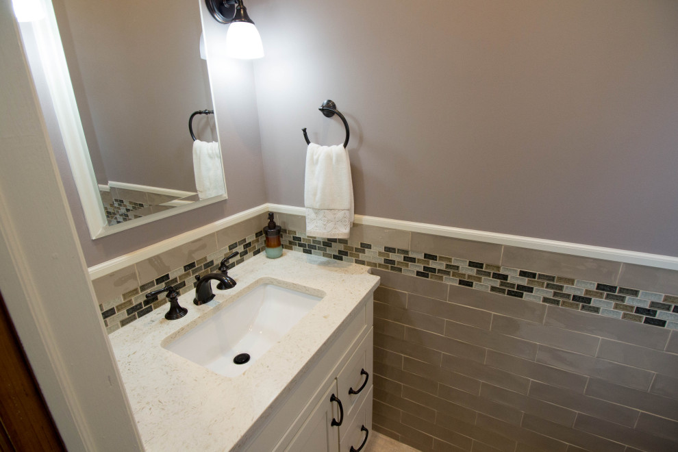 Photo of a small transitional powder room in Newark with shaker cabinets, white cabinets, a two-piece toilet, beige tile, porcelain tile, grey walls, porcelain floors, an undermount sink, engineered quartz benchtops, beige floor, white benchtops and a built-in vanity.